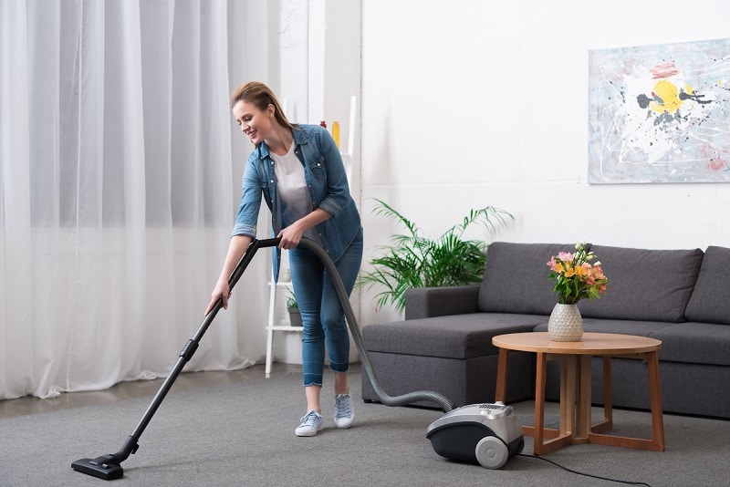 woman vacuuming with canister vacuum