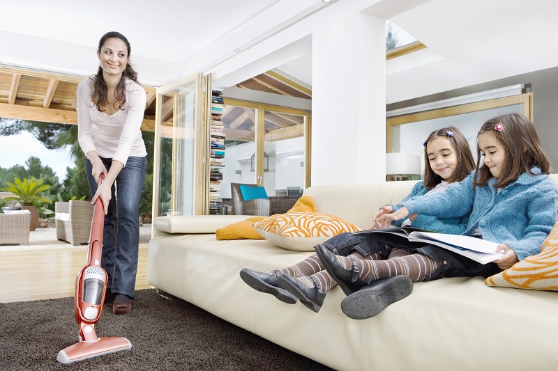 best corded stick vacuum reviews - mom vacuuming with kids on couch
