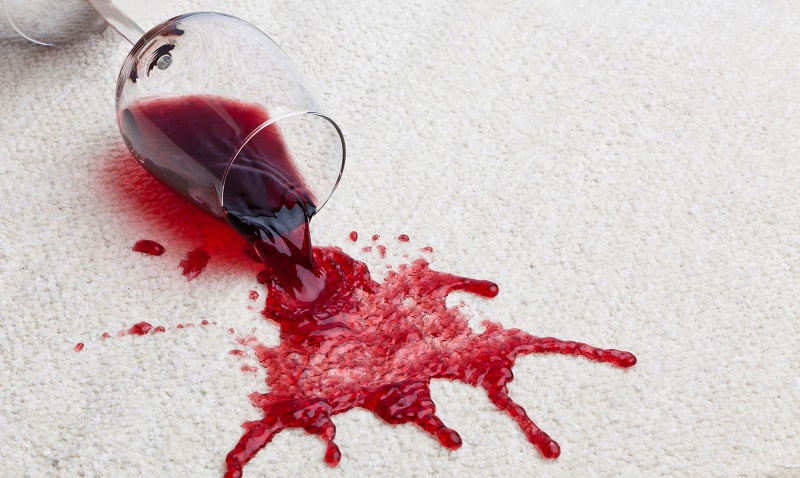 a fallen glass of red wine with a dirty carpet.