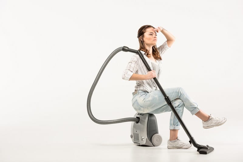 woman sitting on vacuum cleaner - searching for the best vacuum