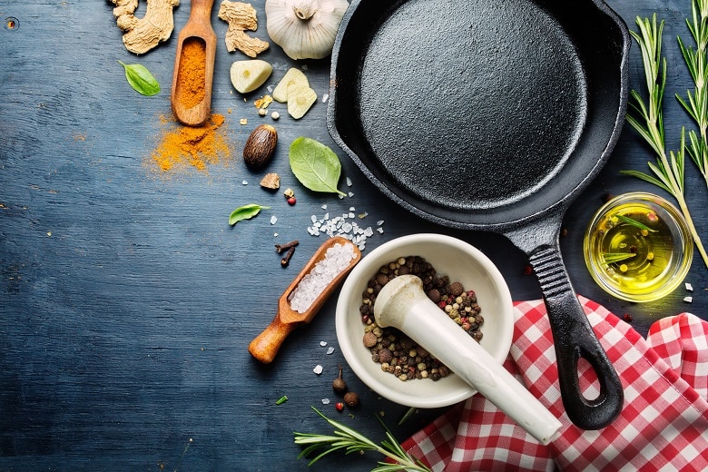 Ingredients for cooking and empty cast iron skillet, pepper and spices.