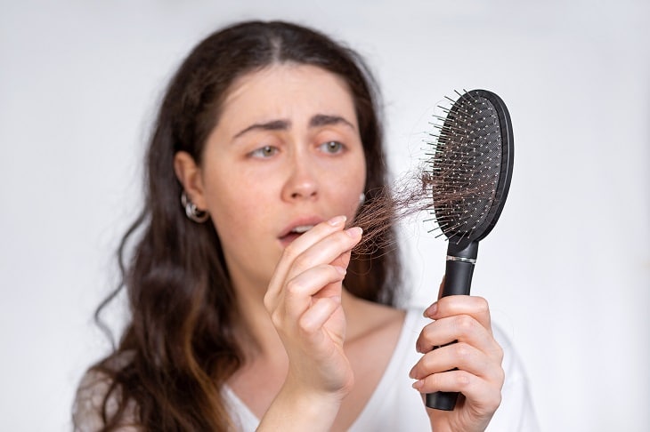 woman frustrated pulling hair from a dirty hair brush